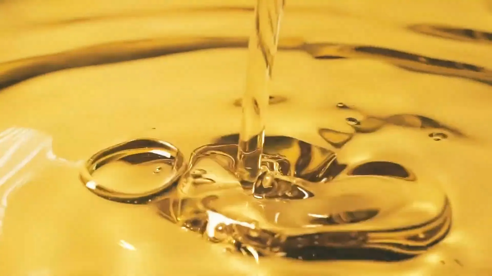Close-up of soybean oil being poured into a container, highlighting its clear texture and color.